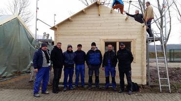 Teilnehmer des Trainingscenters unterstützten beim Aufbau der Holzblockhütten