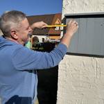 ein Mann misst mit einem Zollstock handwerkliche Arbeiten