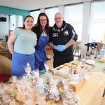 zwei Damen und ein Mann lachen in die Kamera und stehen als Verkäufer am Verkaufstand